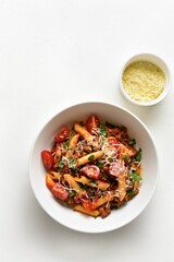 Bowl of bolognese penne pasta with minced meat, tomatoes and greens