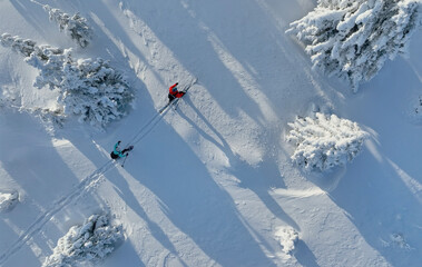 Aerial view of ski touring man and woman with snow shoes crossing winter mountains, fresh snow.