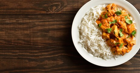 Butter chicken with basmati rice on plate on wooden background