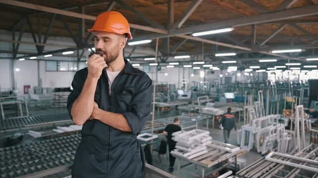 Giving instructions, using radio, walkie talkie. Man is working in the modern factory.