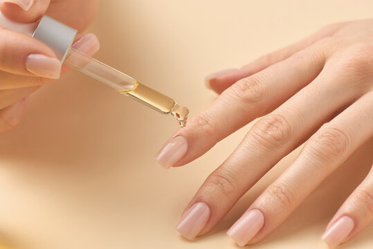 Applying nourishing oil to enhance nail health and appearance during a self-care routine at home