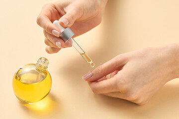 Women's hands apply oil with a pipette to care for the cuticle of nails