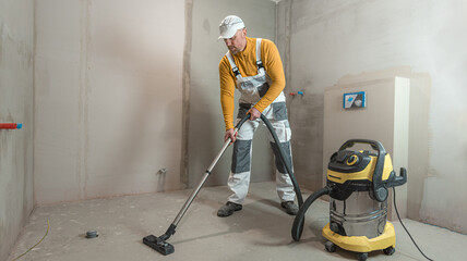 Vacuuming the concrete screed in the bathroom before laying the tiles.