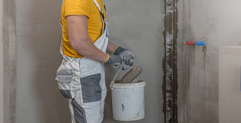 A worker when applies a liquid membrane on the bathroom floor. A worker's hand in a glove uses a...