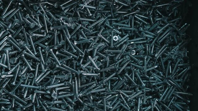 Bunch of galvanized stainless screws with flat countersunk head, hardware background.