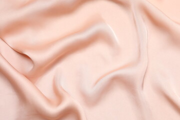 Beige silk satin. Shiny smooth fabric. Soft folds. Luxury background with space for design. Flat table, top view