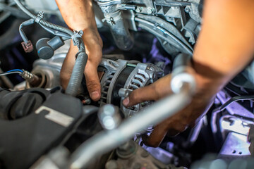 Mechanic is repairing and replacing a battery charger at car service center. Mechanic man holding alternator of the car in repair and maintenance garage.
