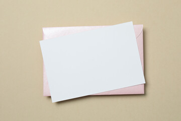 Paper card with envelope on color background. Empty greeting card for text design