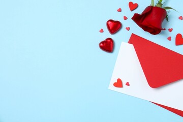 Beautiful red rose, envelope and hearts on color background