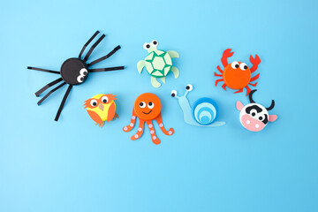 Animal crafts using bottle caps and colored paper on blue background. Flat lay composition with...
