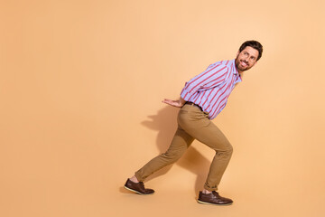 Fototapeta premium Full length photo of handsome young guy look back carry empty space dressed stylish striped formalwear isolated on beige color background