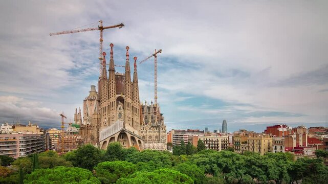BARCELONA, SPAIN - NOVEMBER 9, 2024: Sagrada Familia under construction with cranes among trees and urban skyline in TL Barcelona