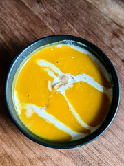 Close up detail of a bowl of pumpkin soup cream serve in a restaurant.