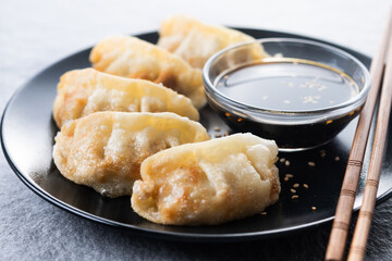 Fried dumplings gyoza with soy sauce on grey stone background. Close up