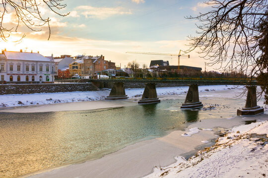 uzhhorod, ukraine - 06 jan, 2019: footbridge on the river uz in winter in evening light. sunny weather. urban landscape of the old city downtown. scenic cityscape scenery