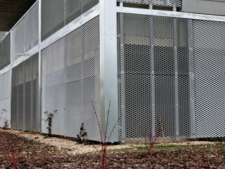 perforated metal sheet in the basement of the house in lining. trellis for climbing plants. the door of the electricity distribution box for the entire residential tower bock building