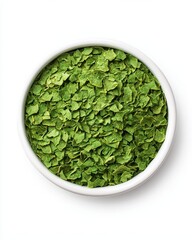 Dried green herbs in a white bowl, showcasing vibrant green flakes, perfect for culinary use and seasoning.