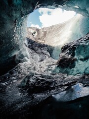 View from inside an ice cave looking out to a bright blue sky, showcasing stunning ice formations.