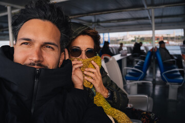Man and woman traveling inside a ferry boat during winter, the woman is covering her face with a scarf, Istanbul, Turkey
