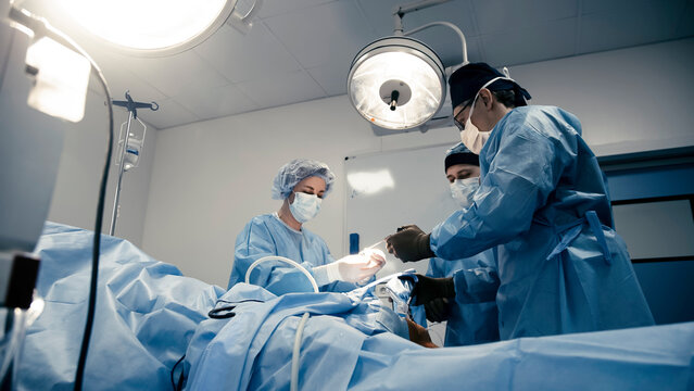 Close-up of professional surgeons performing an operation. During the operation, doctors use modern surgical instruments and equipment. Medical staff working in a hospital operating room.