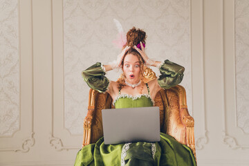 Young woman in historic costume enjoying a modern laptop in a baroque interior
