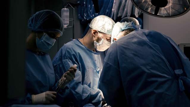 Close-up of professional surgeons performing an operation. During the operation, doctors use modern surgical instruments and equipment. Medical staff working in a hospital operating room. - Powered by Adobe