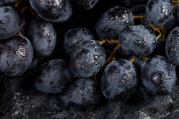 fresh grapes are lying on black paper