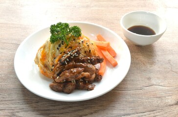 grilled slice pork with egg and sesame dressing teriyaki sauce topping on Japanese rice in plate