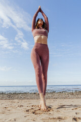 Woman doing yoga on sandy beach, female sport background sea blue sky, sunny day