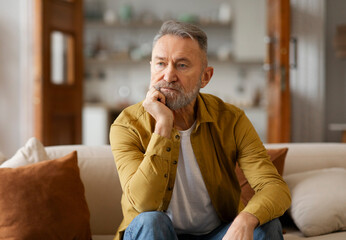 Portrait of thoughtful senior man touching chin, looking away, thinking of problems difficulties,...