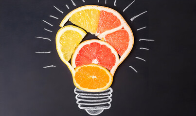 Creative food photography showcasing citrus fruit slices arranged as a lightbulb on a blackboard; symbolizes innovative ideas and fresh thinking.