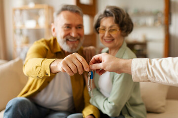 Realtor giving senior couple key to new house, happy older real estate owners making purchase deal....