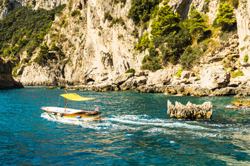 Unrecognizable man steering a small boat along the coast of the island of Capri, Italy.