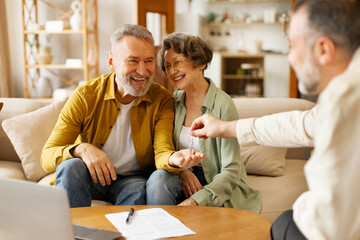 Agent giving keys from new home to excited senior spouses, buying own property, sitting on couch...