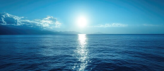 Fototapeta premium Tranquil seascape under a bright sun with calm blue waters reflecting light and serene clouds in the background evoking peace and solitude
