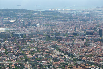 Barcelona cityscape expanding towards the sea with cargo ships waiting in the harbor