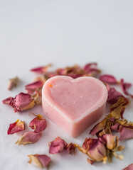 Handmade pink soap bar in shape of heart and dry wild rose petals Spa and selfcare organic product.