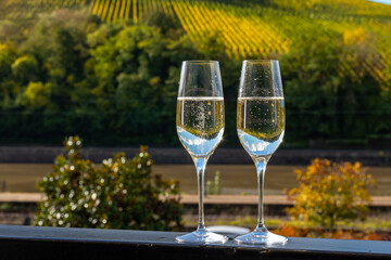 Tasting sparkling white wine, traditional champagne method making of cremant in caves on Moselle river valley in Luxembourg, glasses of wine and view on terraced vineyards