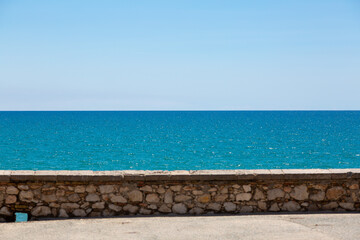 Stone wall separating blue sea and sky on sunny day
