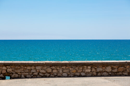 Stone wall separating blue sea and sky on sunny day