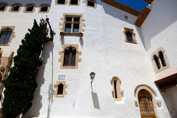 Delivery man riding a scooter in a narrow street with white houses in sitges, spain