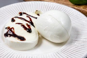 Tasty italian food, fresh white buffalo mozzarella soft cheese balls from Campania served with balsamic vinegar from Modena close up