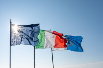 Three large waving flags of ITALY and EUROPEAN UNION and city of Terracina