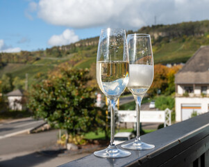 Tasting sparkling white wine, traditional champagne method making of cremant in caves on Moselle river valley in Luxembourg, glasses of wine and view on terraced vineyards