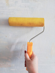 A woman's hand paints a concrete wall with a roller. Painting work. Silicone roller. Types of paint rollers. The design of the house.