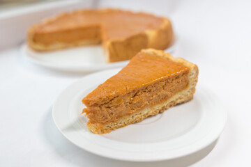 A piece of pumpkin pie with caramel sauce on the white background. Traditional cake. Ready to eat. Cooking concept. Halloween time