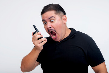 Angry and crass middle-aged man shouting into a two-way radio with white background.