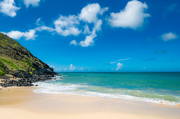 beach with a rocky shoreline and a small hut in the distance