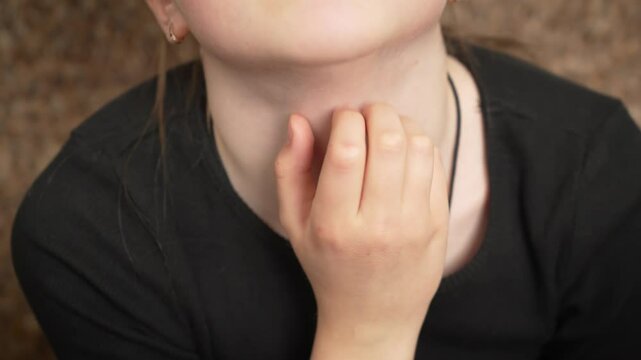 Close up little girl scratching neck. Young child gently rubbing neck detailed view. Portrait small girl lightly itching her neck