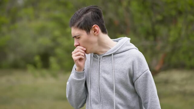 Sick teenage boy with cold or virus coughing, infection prevention and allergies. Adolescent boy coughing due to cold or virus, aware of infection and allergy prevention. Teenager coughing and